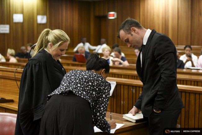 Oscar Pistorius (R) signs documents at the North Gauteng High Court in Pretoria, South Africa for a bail hearing, December 8, 2015. REUTERS/Herman Verwey/Pool