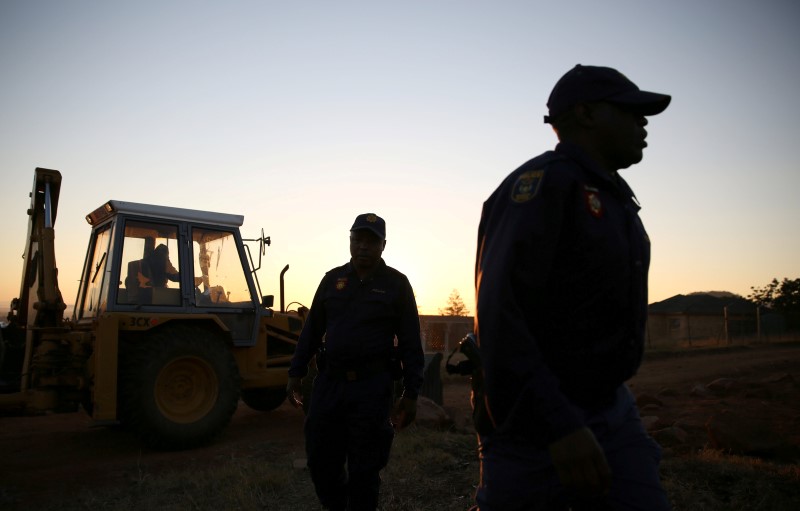 Police officers are seen as a grader removes rocks used by locals to block a road leading to a polling station during tense local municipal elections in Vuwani, South Africa's northern Limpopo province, August 3, 2016. REUTERS/Siphiwe Sibeko