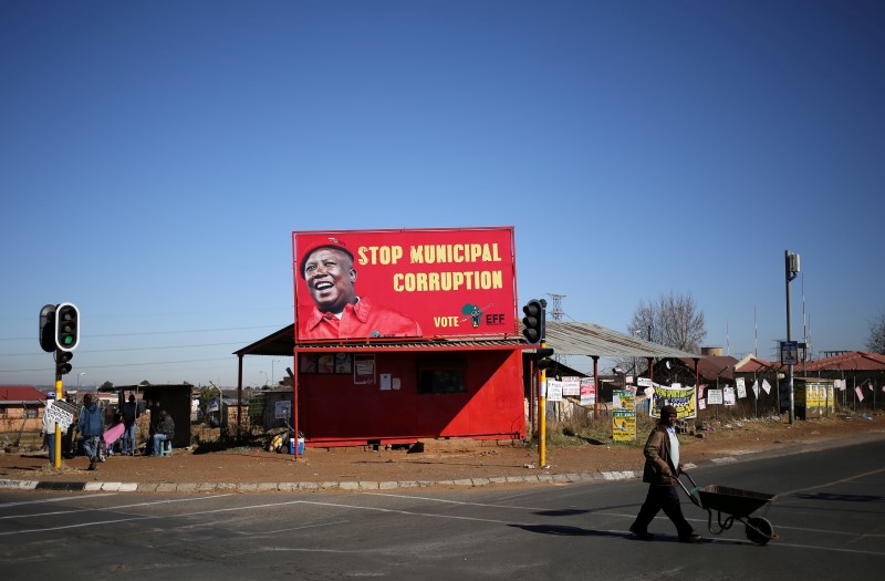 A man pushes a wheelbarrow past a billboard of the Economic Freedom Fighters (EFF), which is led by Julius Malema, President Jacob Zuma's one-time protege and a former ANC youth leader, in Soweto, South Africa, August 5,2016. REUTERS/Siphiwe Sibeko