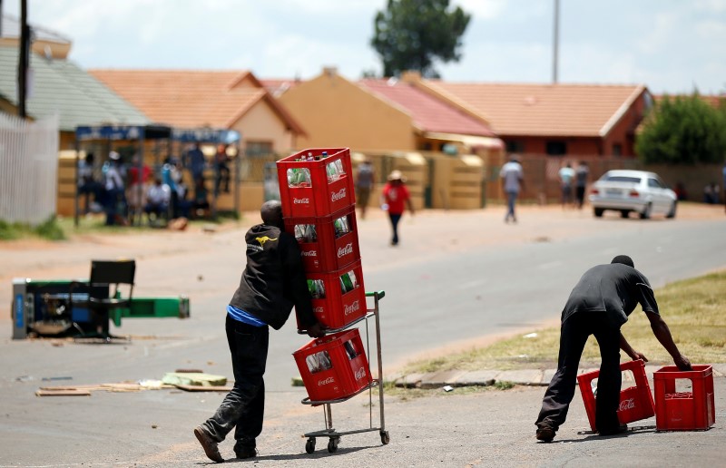 Locals carry soft drinks in crates after looting them from a shop, believed to be owned by a foreigner, during service delivery protests in Mohlakeng