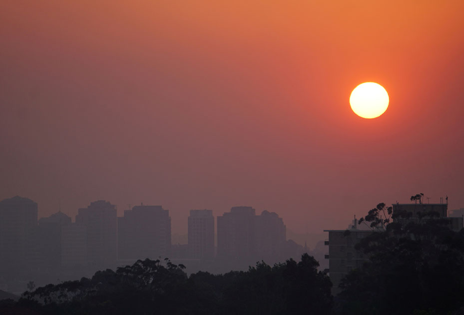 High-rise buildings are seen through smoke from bushfires during sunset in Sydney