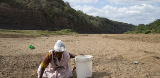 A woman gets water from a well dug in the Black Imfolozi River bed, which is dry due to drought, near Ulundi