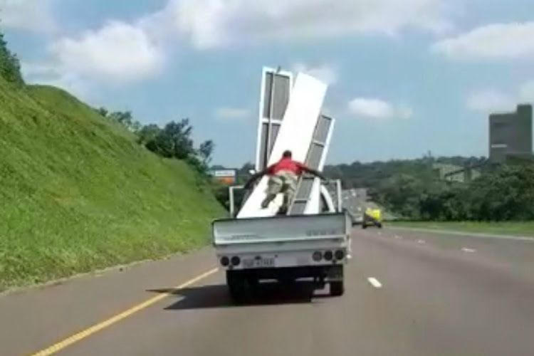 man holds onto scaffolding south africa bakkie