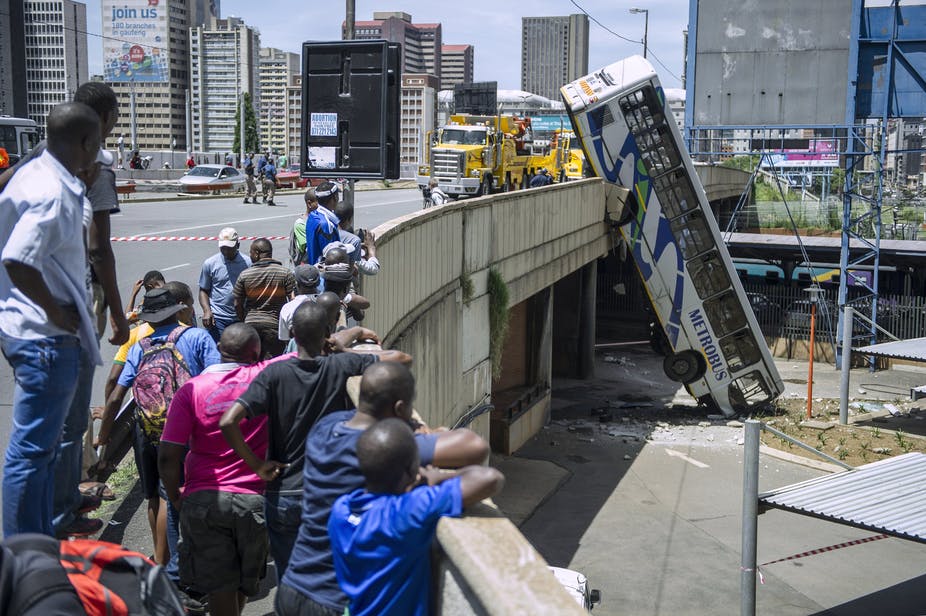 Onlookers gather on Queen Elizabeth bridge to look at a public transport bus that drove over the side of the bridge in Johannesburg, South Africa. Mujahid Safodien/AFP via Getty Images