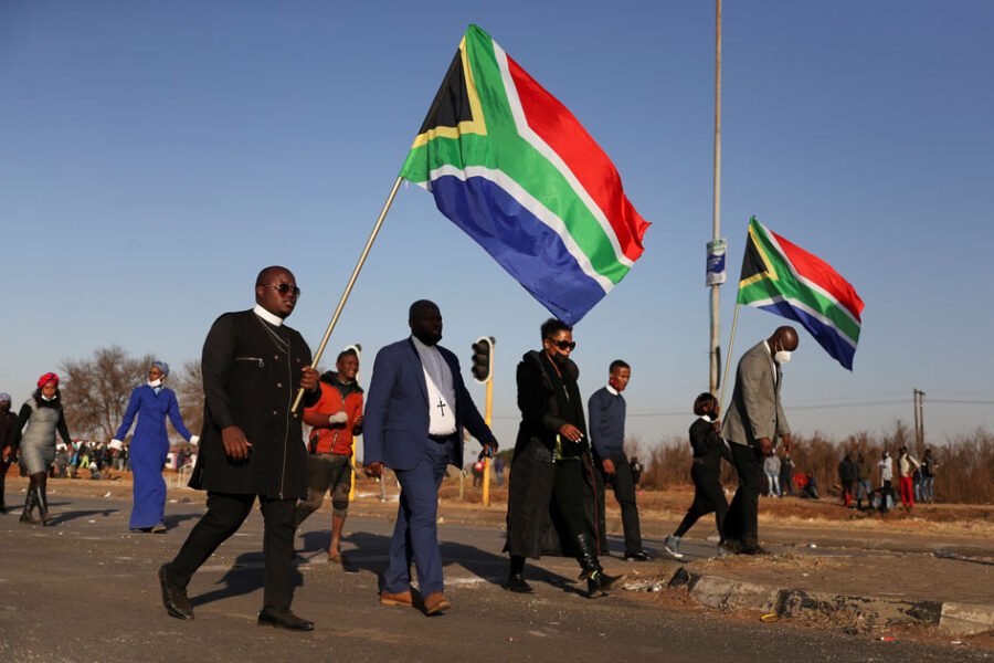 Religious leaders carrying South African flags walk near a looted shopping mall as the country deploys army to quell unrest linked to the jailing of former South African President Jacob Zuma, in Vosloorus, South Africa, July 14, 2021. REUTERS/Siphiwe Sibeko