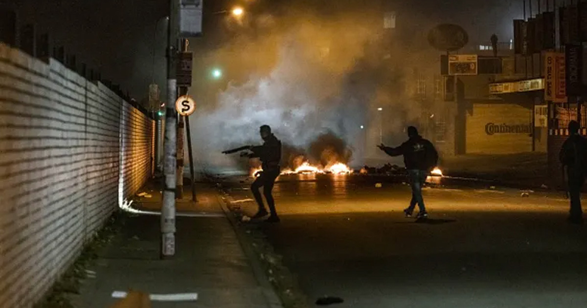 Private armed security officers take a position near a burning barricade during a joint operation with South African Police Service officers in Jeppestown, Johannesburg. Photo by Marco Longari/AFP via Getty Images