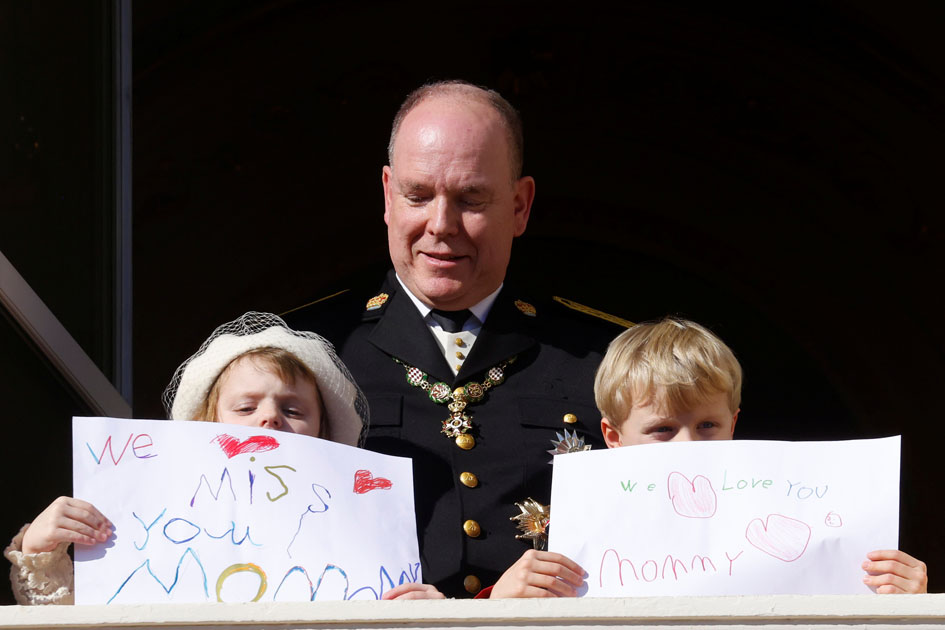 Prince Albert II of Monaco, Prince Jacques and Princess Gabriella holding message which read "We miss you mommy" and "We love you mommy", stand on the palace balcony during the celebrations marking Monaco's National Day in Monaco, November 19, 2021. REUTERS/Eric Gaillard