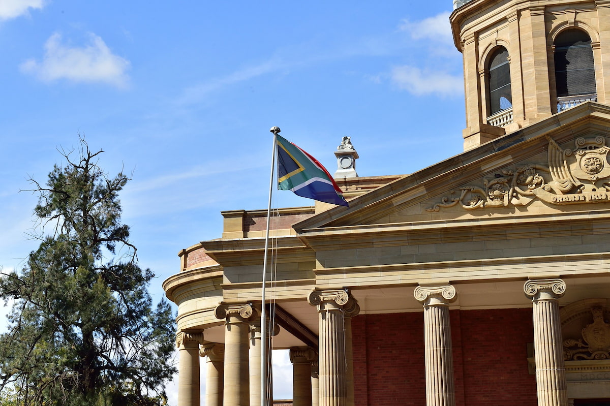 South African flag blowing in front of a government building in the Free State, Bloemfontein. This image accompanies an article that focuses on provincial government salaries in South Africa