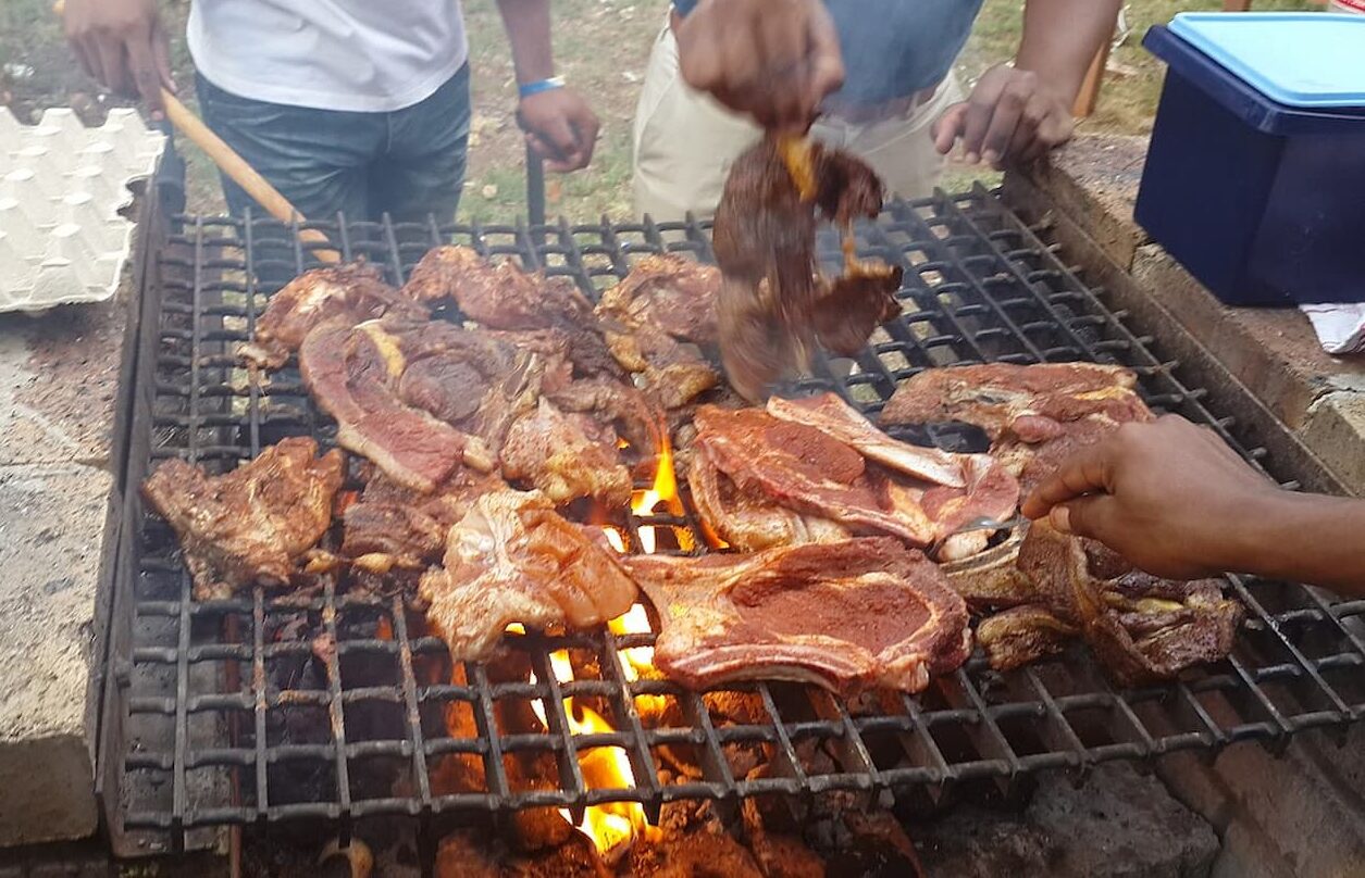 Meat grilling on a braai stand. This image accompanies an article about South Africa's provinces and meat prices in each region