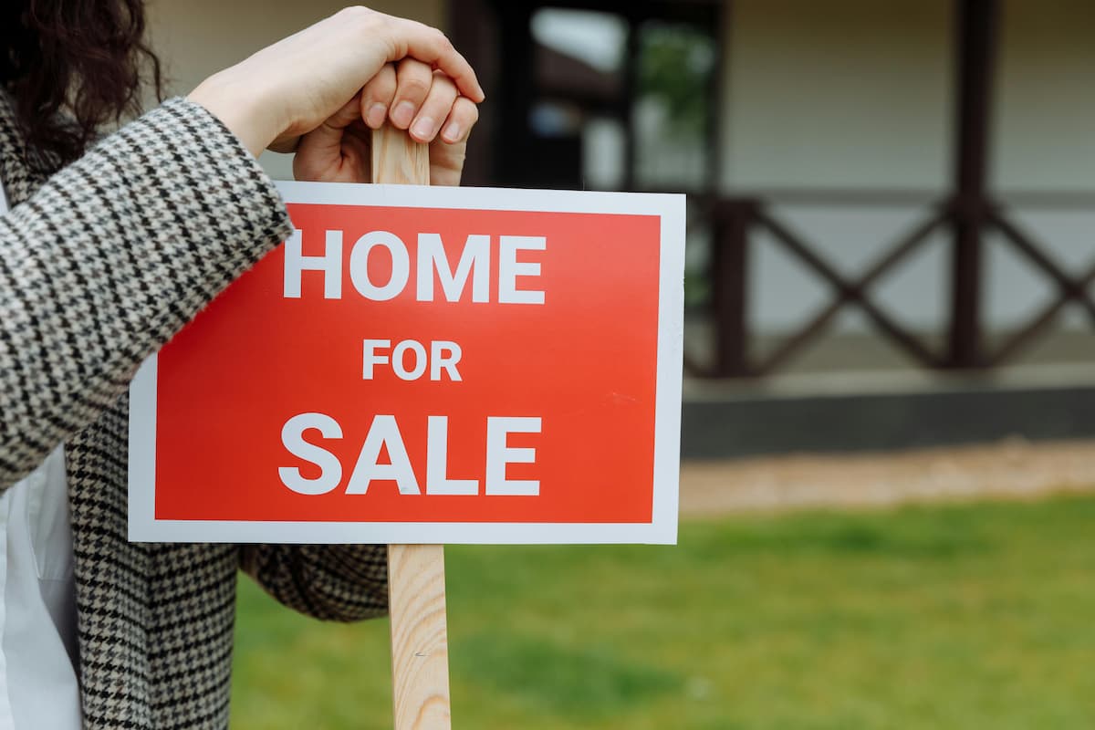 Close-up Shot of a Person Touching the Red Signage on a Wooden Post. This image accompanies an article about the SA property prices and Limpopo's performance