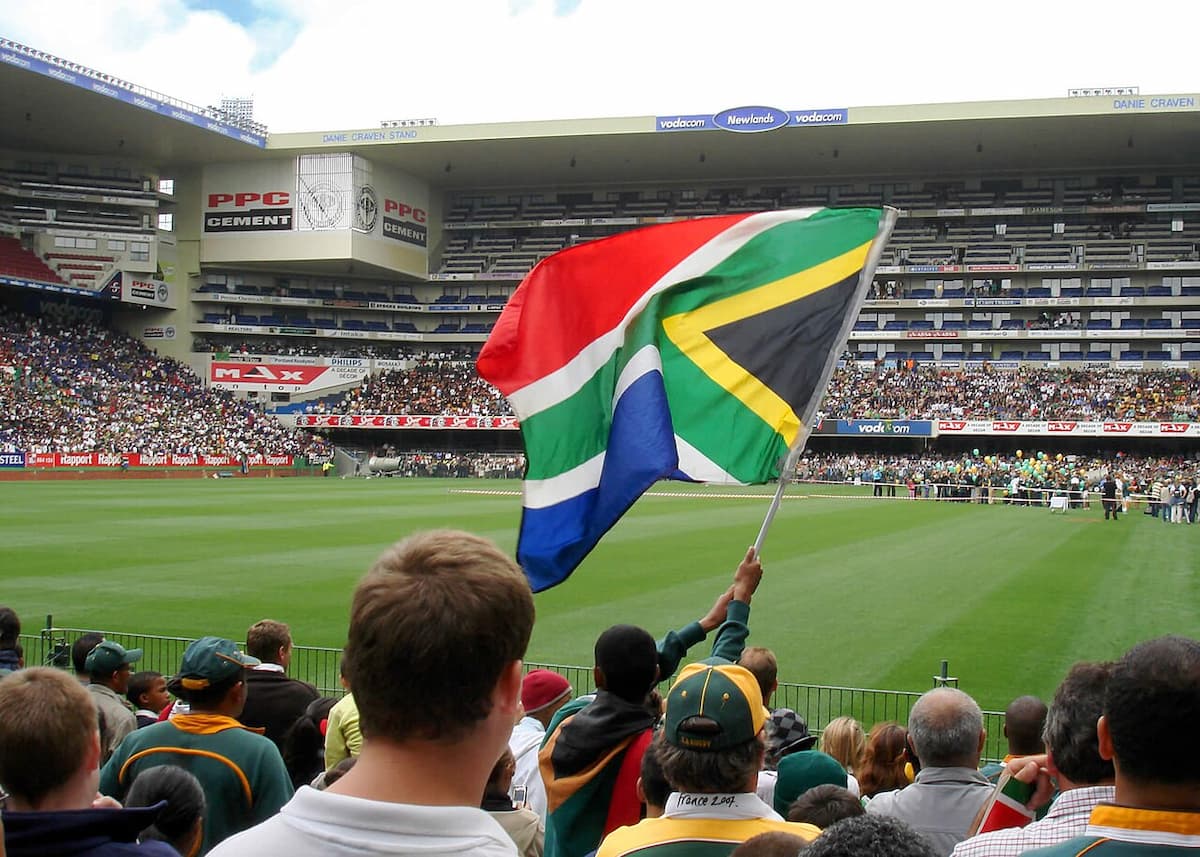 Fans looking on, waving South African flag as they await Springbok squad's arrival at Newlands Rugby Stadium on 29 October 2007. This image accompanies an article about South Africa cracking a top-10 spot on the world's friendliness and politeness list